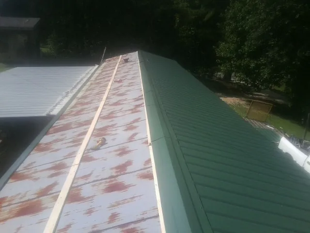 Old rusted panels beside newly installed green metal roofing — Wind Damage Roof Repair by Roofing Brothers in Madison Heights