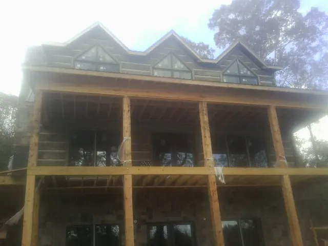 Dormers and porch framing on a large log home under construction — Roof Coating work by our crew in Madison Heights